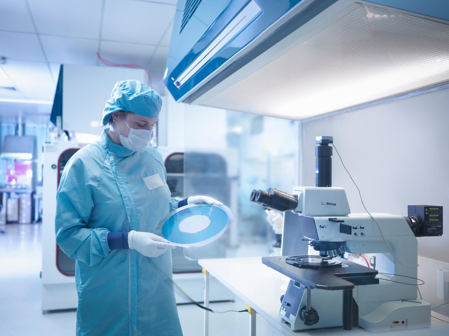 Electronics worker in clean room with silicon wafer Clean Room Garments